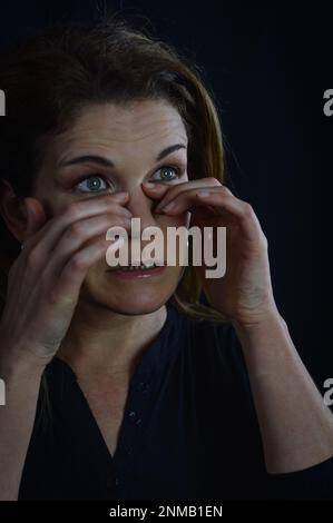 portrait of a beautiful blonde woman who is tired, rubs her eyes trying not to ruin her makeup Stock Photo