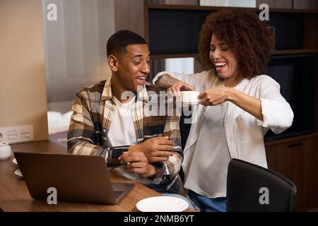 Guy with laptop sits at table in the kitchen area Stock Photo