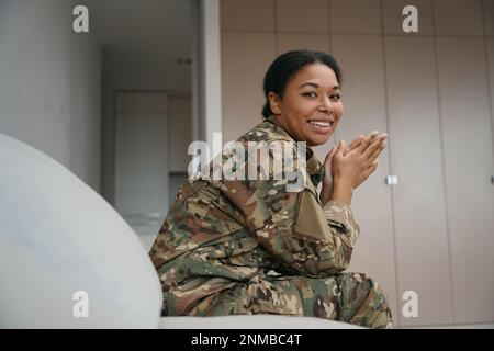 Smiling african american female soldier is sitting in a bright room Stock Photo