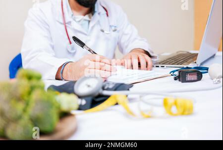 Close-up of nutritionist writing on notepad. Hands of male nutritionist taking notes at his desk, Nutritionist hands taking medical records in the Stock Photo