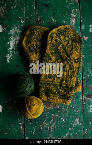 Hand-knitted gloves with pattern next to ball of wool Stock Photo
