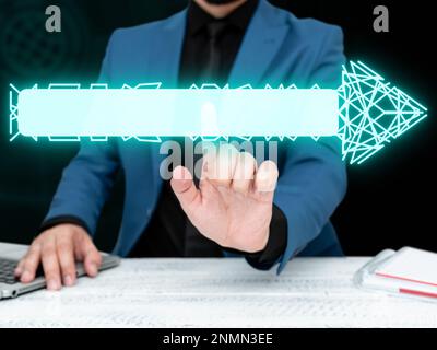 Businessman in blue jacket sitting at the white table and pressing virtual button. Laptop laying on the desk.Futuristic style image with colored glow. Stock Photo