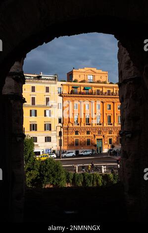 Late afternoon vertical view of two colorful buildings and street through a window opening in the Colisseum. Stock Photo