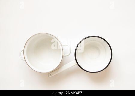Various used enamel kitchen pots on a white background, a set of pots and a bowl of white Stock Photo