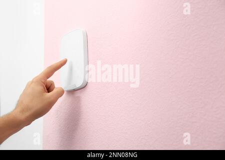 Young man entering code on alarm system keypad indoors, closeup Stock Photo