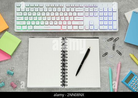 Modern keyboard with RGB lighting and stationery on grey table, flat lay Stock Photo