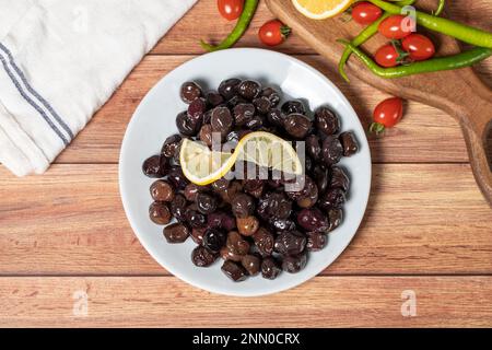 Black olive. Fermented olives and lemon slice in plate. Mediterranean flavors. Top view Stock Photo