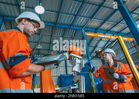 engineer team service programming automated robotic welding arm in modern heavy industry factory Stock Photo