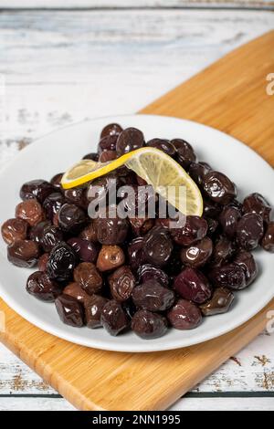 Black olive. Fermented olives and lemon slice in plate. Mediterranean flavors Stock Photo