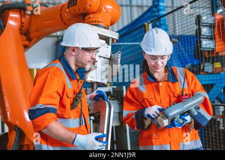 engineer team worker working program robot arm assembly machine in modern metal heavy industry factory Stock Photo