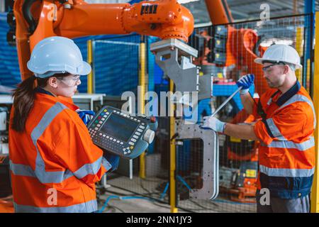 engineer team worker service  robot arm assembly machine in modern metal industry factory Stock Photo