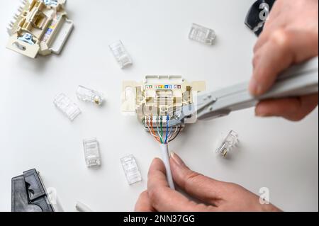 Mounting the RJ45 module, attaching the wire to the computer socket in the room. Stock Photo