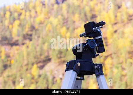 Camera tripod on natural background outdoors, selective focus with copy space. Telescope fasteners, close-up. Fascinating astronomy lessons.Instrument Stock Photo