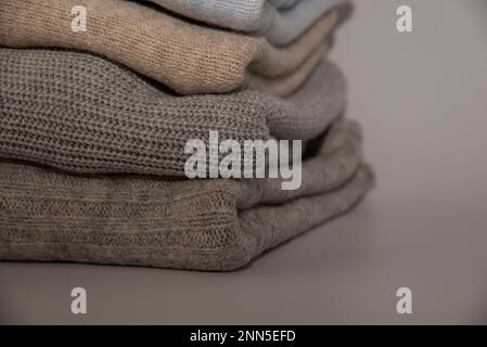 knitted warm pastel color sweaters with different knitting patterns folded in stack, Close up, copy space for text. Stock Photo