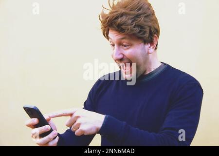 Middle age man making a happy expression while looking at a cellphone Stock Photo