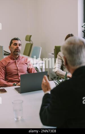 Three business colleagues talking while sitting at the business table at the co working space Stock Photo