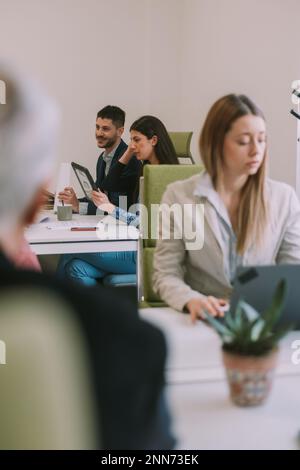 Business colleagues working together on their tablets and laptops while sitting at the office Stock Photo
