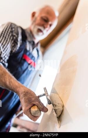 Close up of old man hand working with plaster on walls Stock Photo