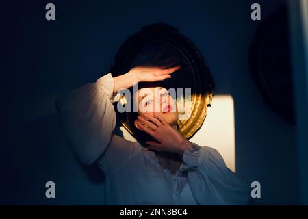 Woman in Shadow with Hands around Face Stock Photo