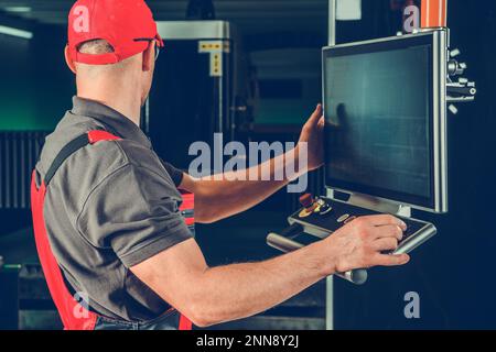 Industrial Machinist Operating the Laser Cutter Machine Console. Metalworking Industry. Stock Photo