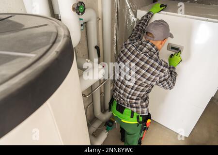 Professional Plumber Performing Modern Residential Heating System Service Check. Stock Photo