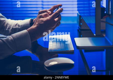 Businessman's Hands Holding Phone. Side View Closeup of Workspace in the Office. Business Theme. Stock Photo