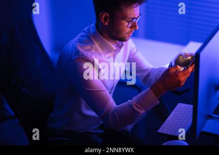 Caucasian Businessman Focused on Data Processing While Working Late in His Office. Business Theme. Stock Photo