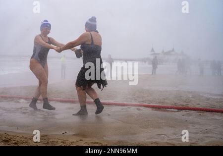 Ahlbeck, Germany. 25th Feb, 2023. Members of ice bathing clubs from Germany and Poland take a so-called ice shower on the beach in front of the pier. Storm and waves had prevented swimming in the Baltic Sea. The winter weather in northern Germany is currently cold and wet. Credit: Stefan Sauer/dpa/Alamy Live News Stock Photo