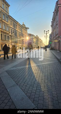 St. Petersburg, Russia - October 25, 2022: People go to work along street in early morning. Silhouettes of passers-by in sun Stock Photo