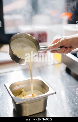The process of making ganache, a filling for a pistachio croissant. The cream affects the white chocolate. Stock Photo