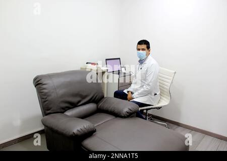 Latin doctor neurologist specialist doing electromyography nerve and muscle study in white office with armchair Stock Photo