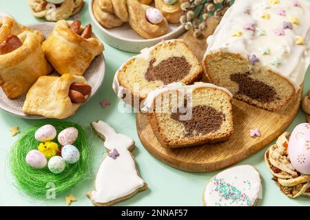 Festive dinner, Easter brunch. Happy Easter holiday food baking puff pastry and cupcake with Easter Bunny on pastel green background. Stock Photo