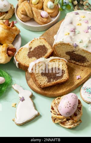 Festive dinner, Easter brunch. Happy Easter holiday food baking puff pastry and cupcake with Easter Bunny on pastel green background. Stock Photo