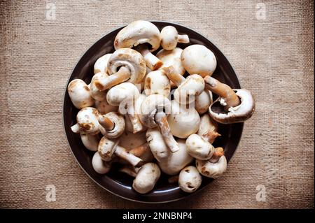 Champignon mushrooms also white button mushrooms on jute background Stock Photo