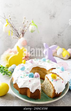 Happy Easter holidays, tasty dessert. Glazed easter lemon cake decorated with confectionery and mini chocolate eggs candy on gray stone background. Co Stock Photo