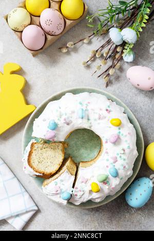 Happy Easter holidays, tasty dessert. Glazed easter lemon cake decorated with confectionery and mini chocolate eggs candy on gray stone background. Vi Stock Photo