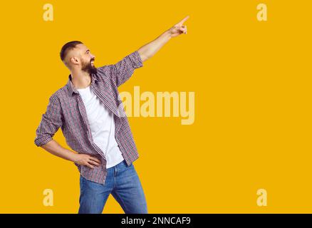 Happy positive young man pointing aside up with finger hand gesture at copy space. Stock Photo