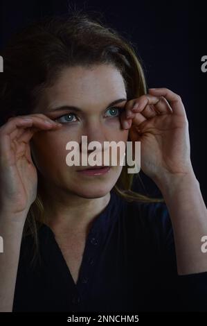 portrait of a beautiful blonde woman who is tired, rubs her eyes trying not to ruin her makeup Stock Photo
