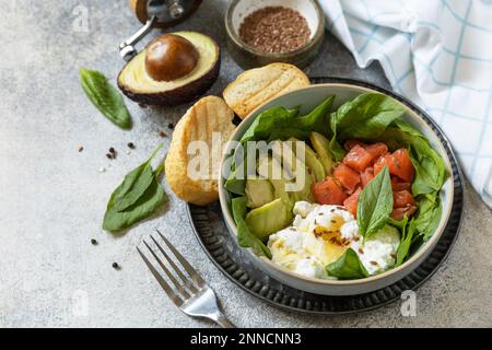Classic breakfast, brunch - with poached egg, avocado, arugula, flax seeds and salted salmon on a gray background.  Copy space. Stock Photo