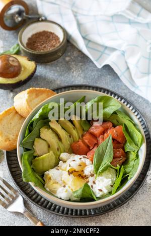 Classic breakfast, brunch - with poached egg, avocado, arugula, flax seeds and salted salmon on a gray background. Copy space. Stock Photo