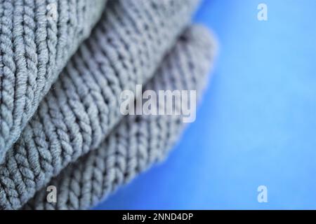 Cozy gray knitted sweater on blue table, copy space. Stock Photo