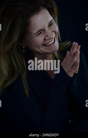 portrait of a beautiful blonde woman who spontaneously laughs and folds her hands Stock Photo