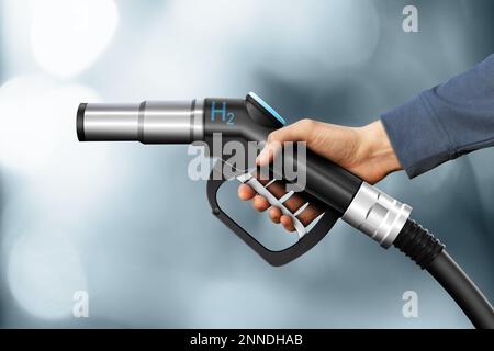 Hand with hydrogen fueling nozzle on a gray background Stock Photo