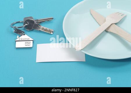 House symbol with silver keys and blank white business card on blue background. Real estate concept Stock Photo