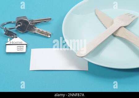 House symbol with silver keys and blank white business card on blue background. Real estate concept Stock Photo