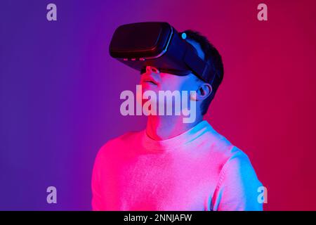 A young man with a virtual reality helmet on his head on a red and blue background. Stock Photo