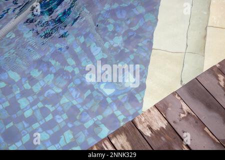 Man cleaning swimming pool with vacuum tube cleaner. Weekly pool maintenance. Pool cleaning service. Stock Photo