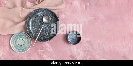Stylish plates and spoon on pink background with space for text Stock Photo