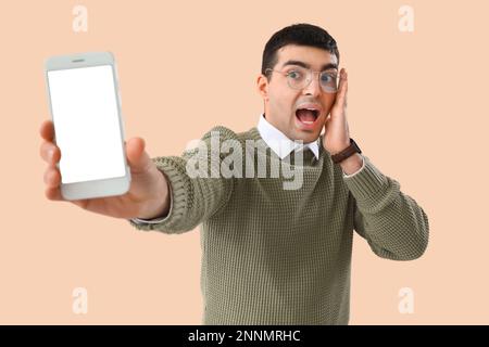 Surprised young man in eyeglasses on beige background Stock Photo