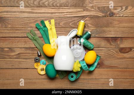 Sewing supplies with Easter rabbit and eggs on wooden background Stock Photo